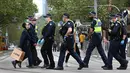 Orang-orang membawa belanjaan mereka saat polisi berpatroli di Melbourne, Australia, Kamis (30/9/2021). Melbourne bergulat dengan lonjakan infeksi Covid-19 di mana sebanyak 1.438 kasus dilaporkan, jumlah harian terbesar sejak awal pandemi. (William WEST / AFP)