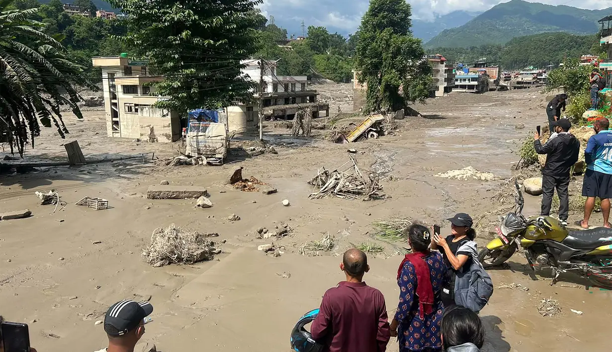 Warga melihat rumah-rumah yang sebagian terendam air berlumpur setelah banjir bandang melanda Trishuli Bazar di distrik Nuwakot, Nepal, Rabu, 26 Agustus 2026. (AFP/ Prakash Mathema)