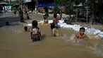 Anak-anak bermain di air banjir setelah hujan lebat di pinggiran Phnom Penh, Kamboja (26/10/2021). Kementerian Sumber Daya Air dan Meteorologi telah mengeluarkan pemberitahuan pada hari Senin tentang situasi cuaca, mengkonfirmasikan risiko banjir di 14 ibu kota dan provinsi Kamboja. (AFP Photo)