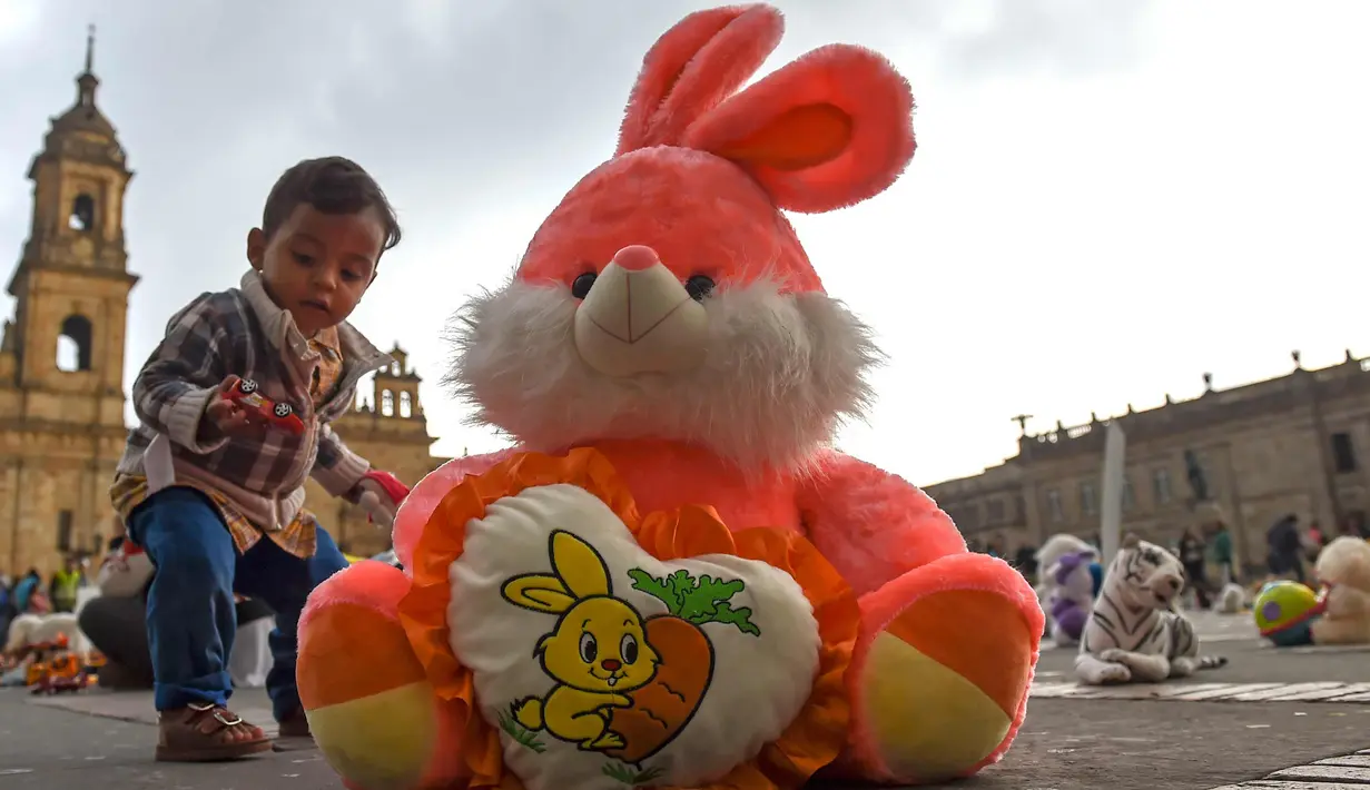 Seorang anak berdiri disamping boneka saat menggelar aksi memprotes penganiayaan terhadap anak sekaligus meningkatkan kesadaran akan tanggung jawab dalam perlindungan anak di Alun-alun Bolivar, Bogota, Kolombia (20/11). (AFP Photo/Raul Arboleda)