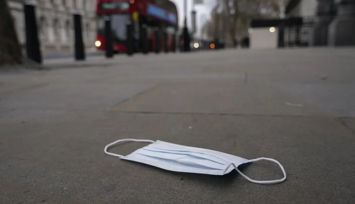 Masker wajah di tanah di Westminster, di London, Kamis (16/12/2021). Inggris mencatat 78.610 infeksi baru pada hari Rabu, 16 persen lebih tinggi dari rekor sebelumnya yang ditetapkan pada Januari. (AP Photo/Alberto Pezzali)
