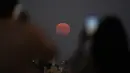<p>Orang-orang mengambil gambar Super Moon terbit di atas Lisbon, Portugal, Kamis (11/8/2022). Bulan Purnama Agustus 2022 akan menjadi fenomena Supermoon terakhir tahun ini. Bulan Purnama Agustus dijuluki "Sturgeon Moon". (AP Photo/Armando Franca)</p>