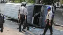 Sejumlah polisi melihat sebuah mobil polisi yang dirusak massa saat bentrok di kawasan Pejompongan, Jakarta, Rabu (7/10/2020). (Liputan6.com/Faizal Fanani)