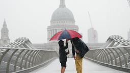 Orang-orang berlindung dengan payung di tengah hujan di London, Rabu (17/8/2022). Setelah berminggu-minggu cuaca terik, yang telah menyebabkan kekeringan dan membuat tanah kering, peringatan badai petir kuning dari Kantor Meteorologi memperkirakan hujan lebat dan badai petir yang bisa melanda bagian Inggris dan Wales. (Victoria Jones/PA via AP)