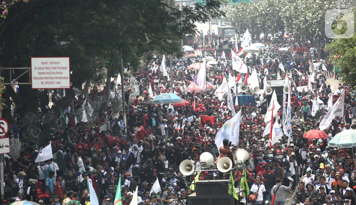 Massa buruh turun ke jalan saat gelar aksi di sekitar Gedung DPR RI, Jakarta, Rabu (2/10/2019). Puluhan ribu buruh dari berbagai daerah berunjuk rasa dalam rangka menolak revisi UU Ketenagakerjaan dan PP Nomor 78 Tahun 2015 serta menolak kenaikan iuran BPJS Kesehatan. (merdeka.com/Iqbal S. Nugroho)