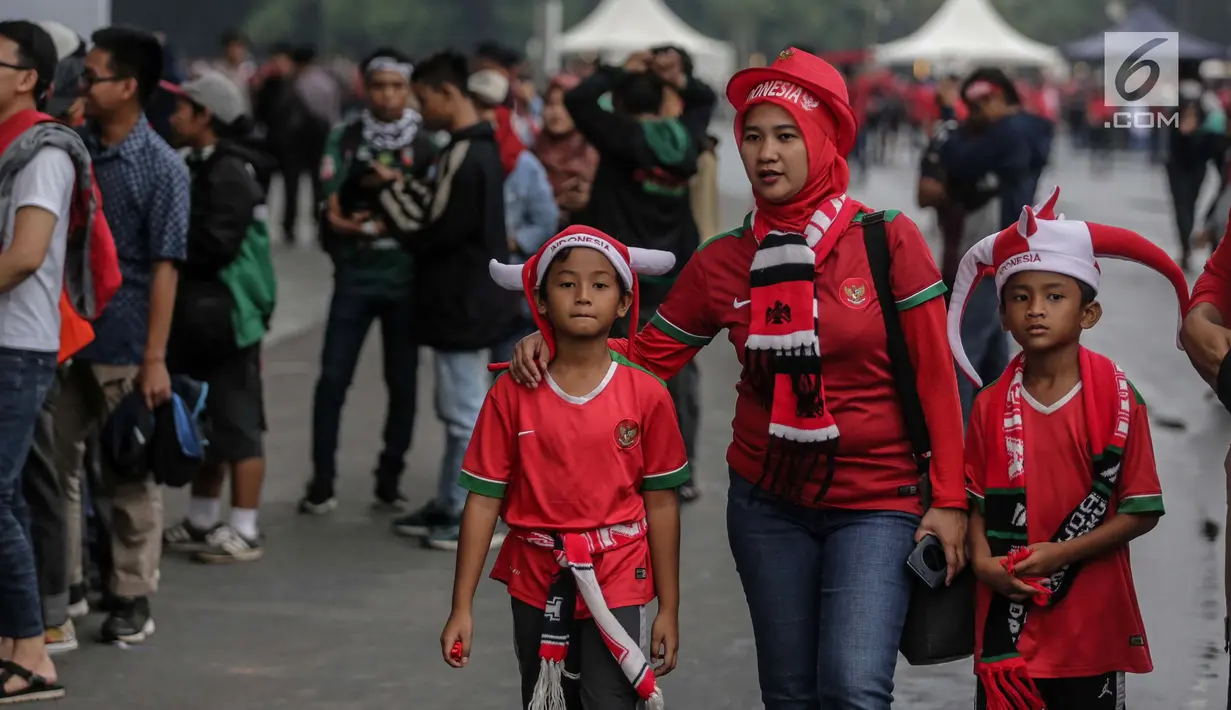 Seorang ibu memabawa dua anaknya menyaksikan Timnas Indonesia kontra islandia di Stadion Gelora Bung Karno (GBK), Senayan, Jakarta, Minggu (14/1). Timnas Indonesia akan berlaga melawan Islandia malam nanti. (Liputan6/Faizal Fanani)