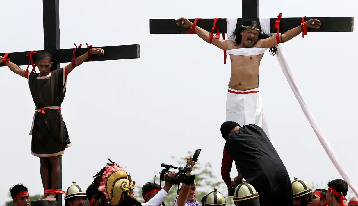 Ekspresi Ruben Enaje (kanan) saat tangannya dipaku ke tiang salib di Pampanga, Filipina, Jumat (30/3). Aksi Ruben kali ini memasuki tahun ke 32 yang dilakukan secara berturut-turut. (AP Photo/Aaron Favila)