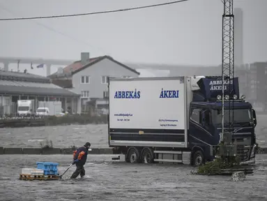 Seorang pria berjalan di sepanjang Fiskhamnen (pelabuhan nelayan) yang banjir setelah sungai Gota Alv meluap akibat hujan deras di Gothenburg, Swedia, Selasa, 8 Agustus 2023.  (Björn Larsson Rosvall/TT News Agency via AP)