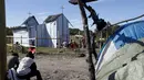 Imigran gelap menunggu di dekat kamp sementara mereka sebelum mengikuti misa di gereja darurat di sekitar pelabuhan Calais, Prancis, Minggu (2/8/2015). Sebelumnya ratusan imigran memaksa masuk Prancis melalui Terowongan Channel. (REUTERS/Pascal Rossignol)