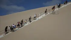 Orang-orang menaiki tangga di Dune du Pilat, bukit pasir tertinggi di Eropa, pada hari pembukaannya kembali setelah kebakaran hebat menghancurkan 7000 hektar hutan La Teste-de-Buch di dekatnya, di Pyla sur Mer , di Gironde, barat daya Prancis (27/7/2022). (AFP/Romain Perrocheau)