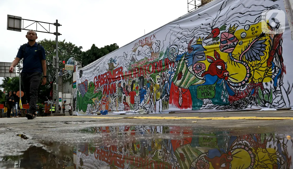 Warga berjalan di samping proyek revitalisasi Taman Ismail Marzuki (TIM) yang dipenuhi lukisan bentuk protes, Jakarta, Sabtu (29/2/2020). Kebijakan Pemprov DKI Jakarta merevitalisasi TIM dinilai cacat prosedural karena tidak pernah dibicarakan dengan seniman sebelumnya. (Liputan6.com/Johan Tallo)