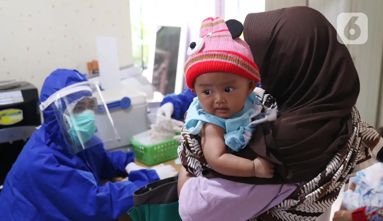 Bidan mengenakan alat pelindung diri (APD) saat melakukan imunisasi kepada bayi di Puskesmas Karawaci Baru, Tangerang, Banten, Rabu (13/5/2020). Pelayanan imunisai sesuai jadwal ini diberikan kepada bayi untuk menambah kekebalan imun tubuh. (Liputan6.com/Angga Yuniar)