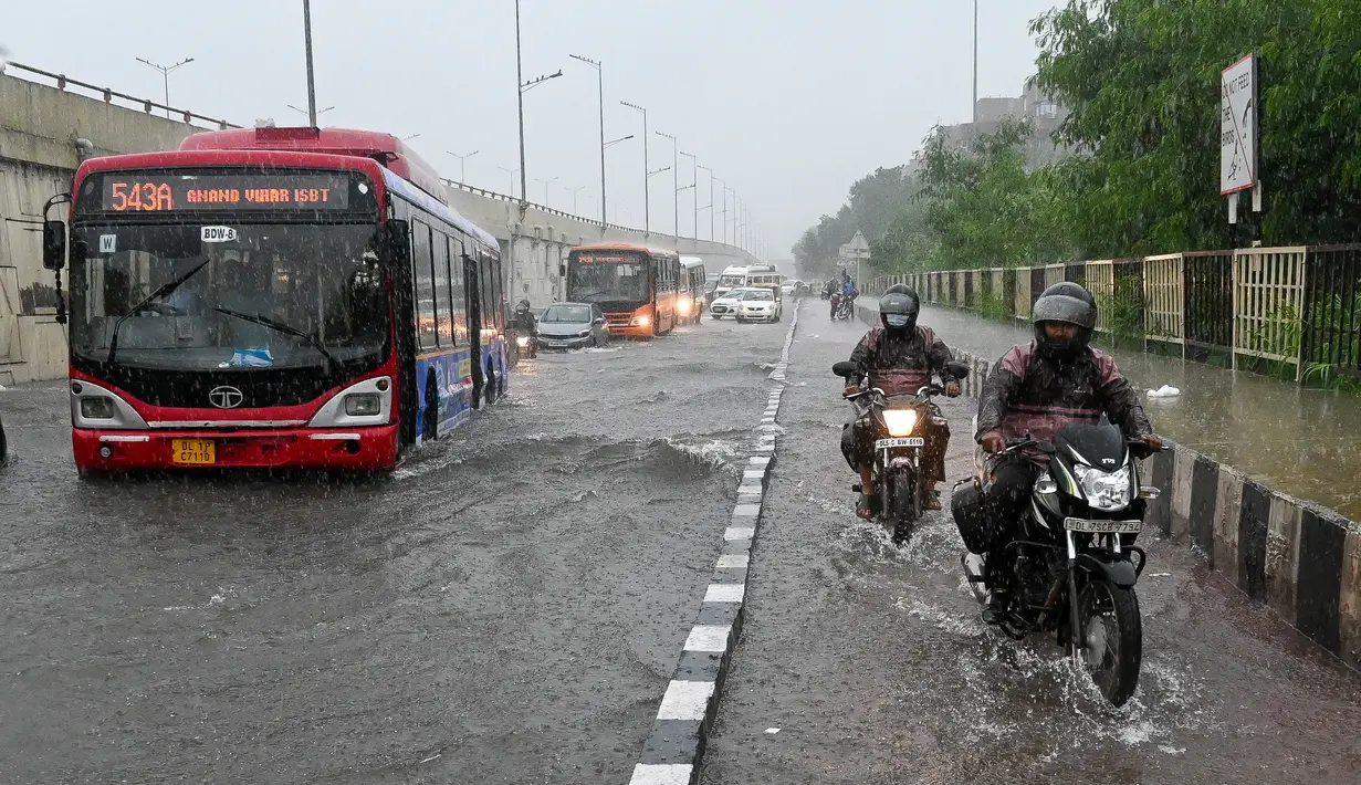 Sebuah bus melewati jalan yang tergenang air saat hujan lebat di New Delhi, India (1/9/2021). Hujan lebat yang terus mengguyur Kota New Delhi dalam dua hari berturut-turut dengan intentitas tinggi di hari kedua telah menyebabkan genangan banjir. (AFP/Prakash Singh)