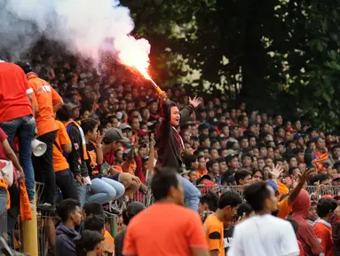 Suporter tim Macan Kemayoran menyalakan flare saat menyaksikan laga uji coba antara Persija melawan Barito Putera di Stadion Bea Cukai Rawamangun, Jakarta, Selasa (5/4/2016). Laga uji coba berakhir imbang 2-2. (Liputan6.com/Helmi Fithriansyah)
