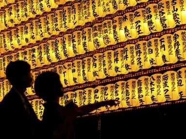 Para pengunjung melihat lentera kertas saat Festival Mitama di Kuil Yasukuni, Tokyo, Jepang, Rabu (14/7/2021). Festival Mitama dirayakan sejak 1947 untuk menghormati jiwa para arwah yang diabadikan serta tentara yang gugur dari perang Jepang di masa lalu. (BEHROUZ MEHRI/AFP)