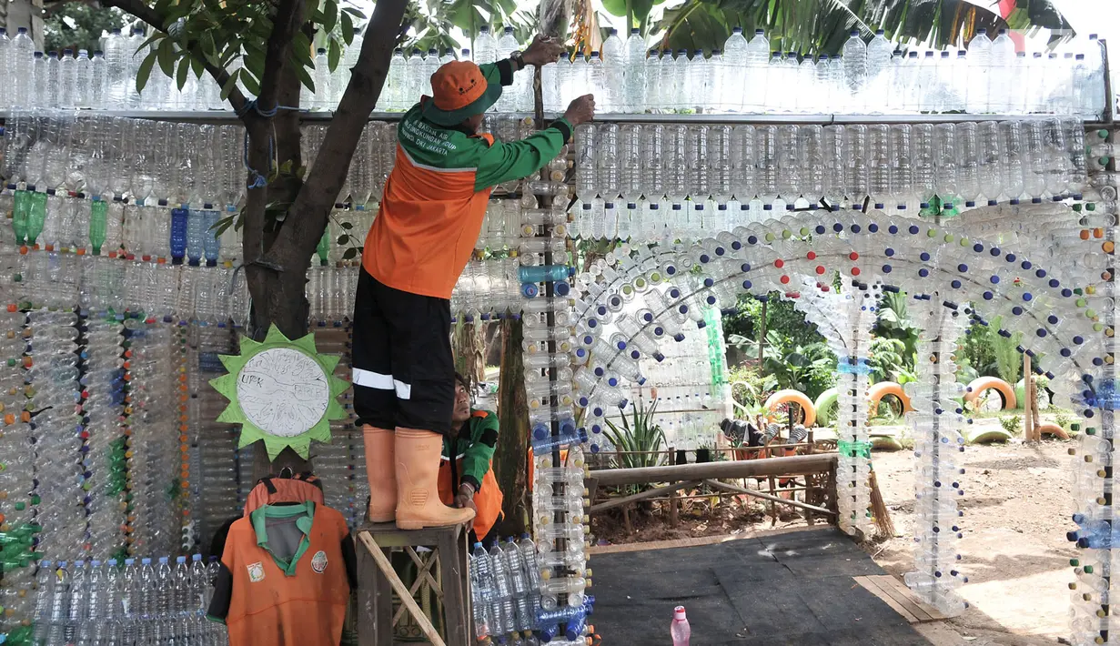 Petugas UPK Badan Air DLH DKI Jakarta saat merapikan instalasi botol yang menghiasi pos di Pasar Rebo, Jakarta, Selasa (12/3). Lebih dari seribu botol plastik bekas dipasang untuk menghiasi Pos  UPK Badan Air di Pasar Rebo. (merdeka.com/Iqbal Nugroho)