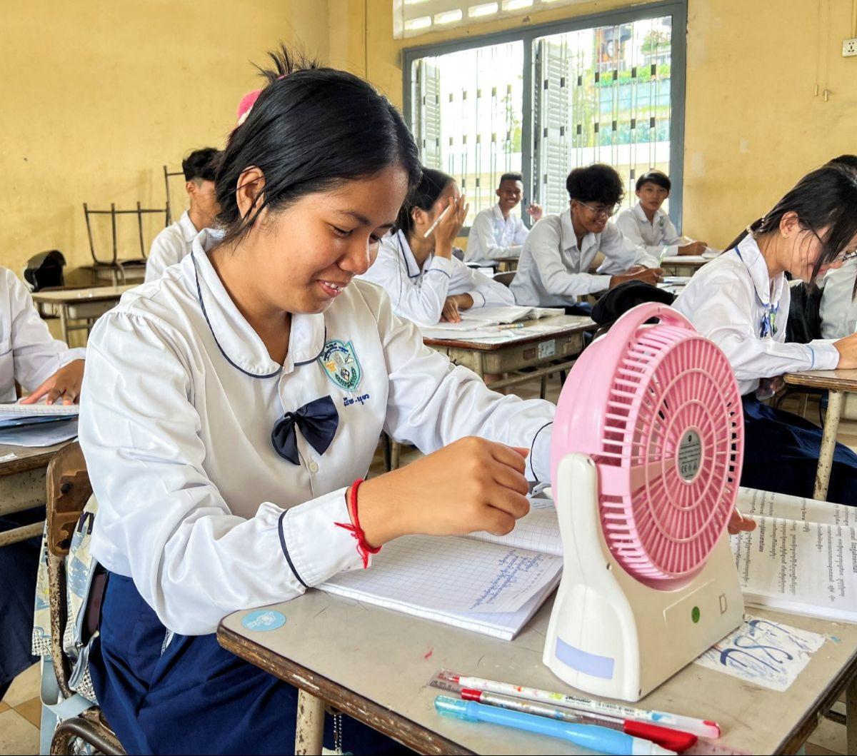 Seorang murid menggunakan kipas angin untuk menyegarkan diri selama kebiatan belajar di sebuah sekolah di Phnom Penh, Kamboja, pada Kamis (2/5/2024). Gelombang panas yang membuat suhu naik ekstrem tengah 'memanggang' Kamboja.&nbsp;REUTERS/Cha Tha Lach