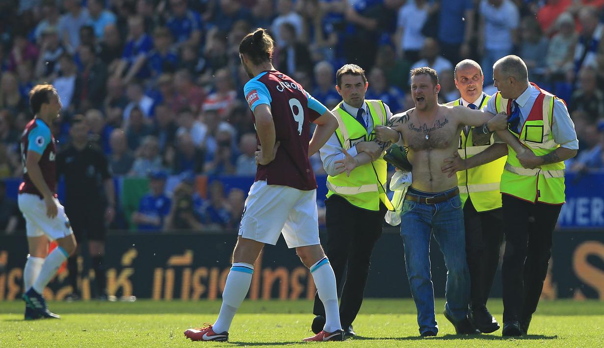 Petugas keamanan menangkap suporter yang trun ke dalam lapangan saat laga Leicester City melawan West Ham Unitd di King Power Stadium, Leicester, (5/5/2018).  West Ham menang 2-0. (AFP/Lindsey Parnaby)
