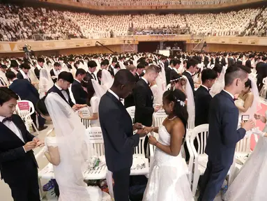 Pasangan pengantin bertukar cincin dalam pernikahan massal di Cheong Shim Peace World Center, Gapyeong, Korea Selatan, Senin (27/8). Acara ini diikuti sekitar 3.800 pasangan pengantin. (AP Photo/Ahn Young-joon)
