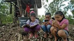 Siswa sekolah dasar mengikuti pembelajaran secara online menggunakan smartphone mereka di bukit Temulawak, Yogyakarta, Jumat (8/5/2020). Mereka harus ke atas bukit untuk mendapat sinyal yang bagus agar kegiatan belajar secara online dapat berlangsung. (AGUNG SUPRIYANTO/AFP)
