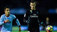 Pemain Real Madrid, Gareth Bale dan bek Celta Vigo, Hugo Mallo berebut bola pada pertandingan pekan ke-18 La Liga kontra Celta Vigo di Estadio de Balaidos, Minggu (7/1). Sempat unggul, Madrid akhirnya harus puas dengan skor akhir 2-2. (MIGUEL RIOPA/AFP)