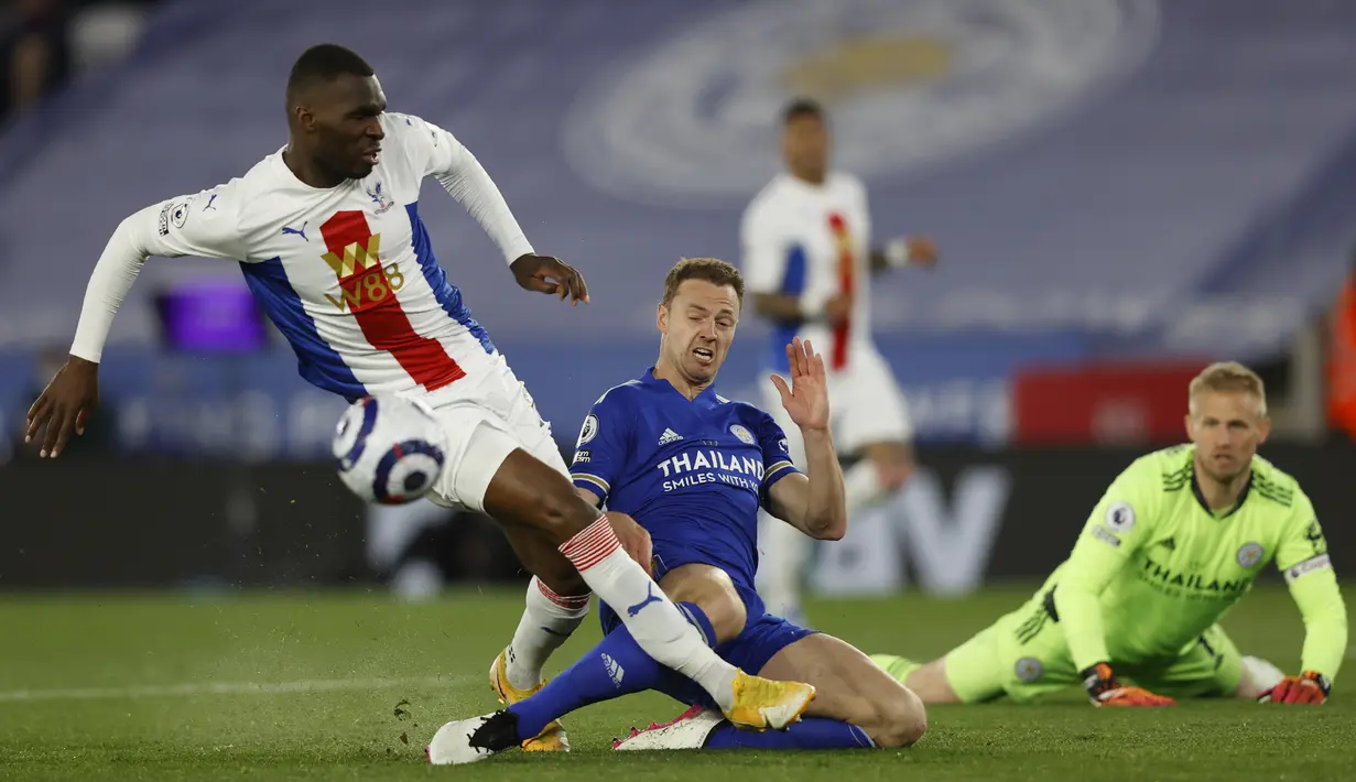 Penyerang Crystal Palace, Christian Benteke berebut bola dengan bek Leicester City, Jonny Evans dalam lanjutan Premier League digelar di King Power Stadium, Selasa (27/4/2021) dini hari WIB. Leicester City memetik kemenangan penting 2-1 di kandang atas Crystal Palace. (Adrian Dennis/Pool via AP)