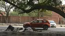 Pria tidur di pembatas jalan di salah satu sudut New Delhi ketika ibu kota India melanjutkan penguncian atau lockdown pada Rabu (5/5/2021). Pemerintah India menghadapi seruan lockdown nasional secara total untuk memperlambat gelombang besar infeksi virus corona. (TAUSEEF MUSTAFA/AFP)