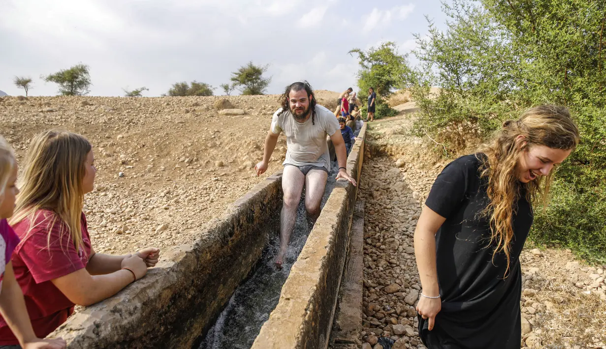 Warga Israel bermain air di sebuah kanal kecil di Desa Al-Auja selama perayaan keagamaan Yahudi dalam Festival Sukkot di Tepi Barat (17/10/2019). Festival Yahudi di Sukkot memperingati pengembaraan padang pasir alkitabiah orang Israel setelah eksodus mereka dari Mesir. (AFP Photo/Menahem Kahana)