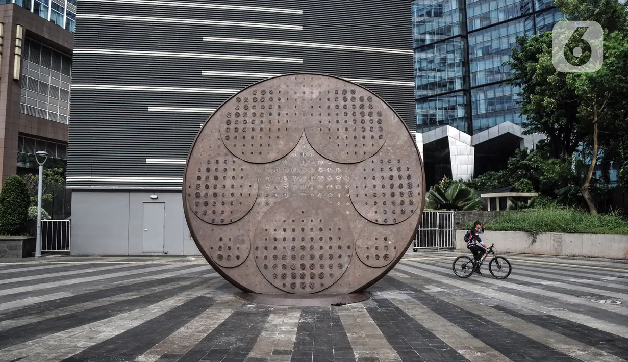 Pesepeda melintas dekat Tugu Sepeda di Jalan Jenderal Sudirman, Jakarta Pusat, Minggu (23/10/2022). Tugu Sepeda berbentuk roda setinggi 5,7 meter. (merdeka.com/Iqbal S. Nugroho)