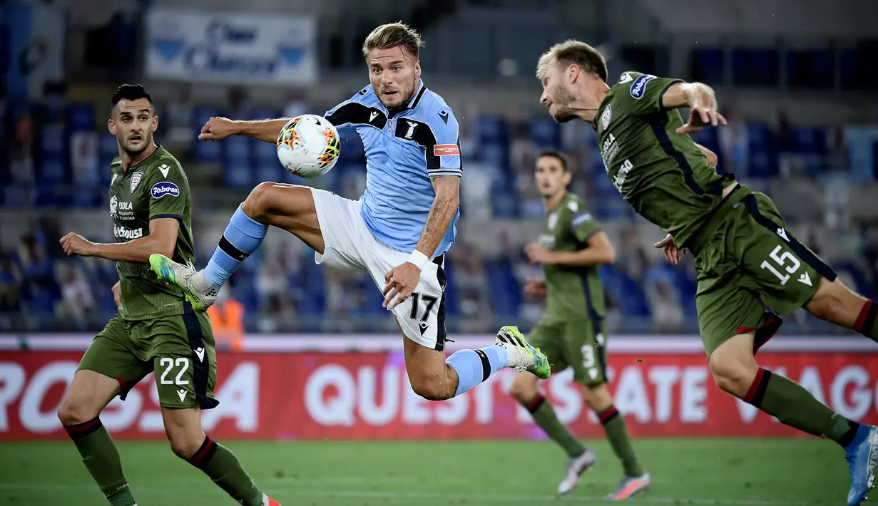 Penyerang Lazio, Ciro Immobile, berebut bola dengan bek Cagliari, Ragnar Klavan, pada laga lanjutan Serie A pekan ke-35 di Stadio Olimpico, Jumat (24/7/2020) dini hari WIB. Lazio menang 2-1 atas Cagliari.(AFP/Filippo Monteforte)