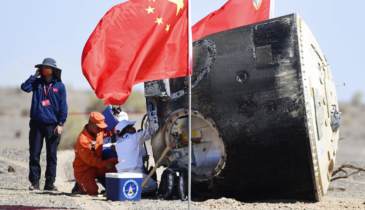 Para pekerja membuka kapsul pesawat ruang angkasa berawak Shenzhou-12 setelah berhasil mendarat di lokasi pendaratan Dongfeng di Daerah Otonomi Mongolia Dalam, China, 17 September 2021. Trio astronot China kembali ke Bumi setelah 90 hari tinggal di Stasiun Luar Angkasa. (Ren Junchuan/Xinhua via AP)