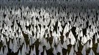 Matahari bersinar di atas bendera putih yang ditanam untuk mengenang warga Amerika yang meninggal karena COVID-19 di dekat Stadion RFK di Washington, Selasa (27/10/2020). Instalasi seni Suzanne Brennan Firstenberg itu disebut "In America, How Could This Happen.” (AP/Patrick Semansky)