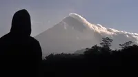 Seorang pria menyaksikan Gunung Merapi memuntahkan asap vulkanik di Yogyakarta, Indonesia, Selasa, (22/5). Pihak berwenang meningkatkan kewaspadaan terhadap Gunung Merapi yang bergejolak di pulau Jawa. (AP Photo/Slamet Riyadi)