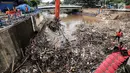 Sebuah eskavator mengangkat tumpukan sampah di Pintu Air Manggarai Jakarta, Senin (12/11). Hujan deras yang mengguyur pada Minggu malam membuat sampah yang terbawa arus Kali Ciliwung menutupi Pintu Air Manggarai. (Liputan6.com/Fery Pradolo)