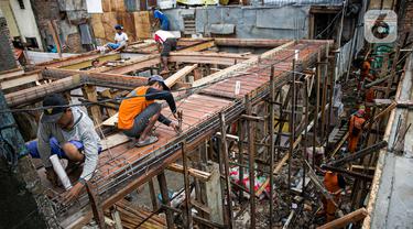 Para pekerja menyelesaikan pembangunan rumah panggung di dekat bantaran Kali Ciliwung, Kampung Melayu, Jakarta, Rabu (7/4/2021). Pemerintah Provinsi DKI Jakarta melakukan renovasi terhadap 40 hunian warga Kampung Melayu menjadi rumah panggung. (Liputan6.com/Faizal Fanani)