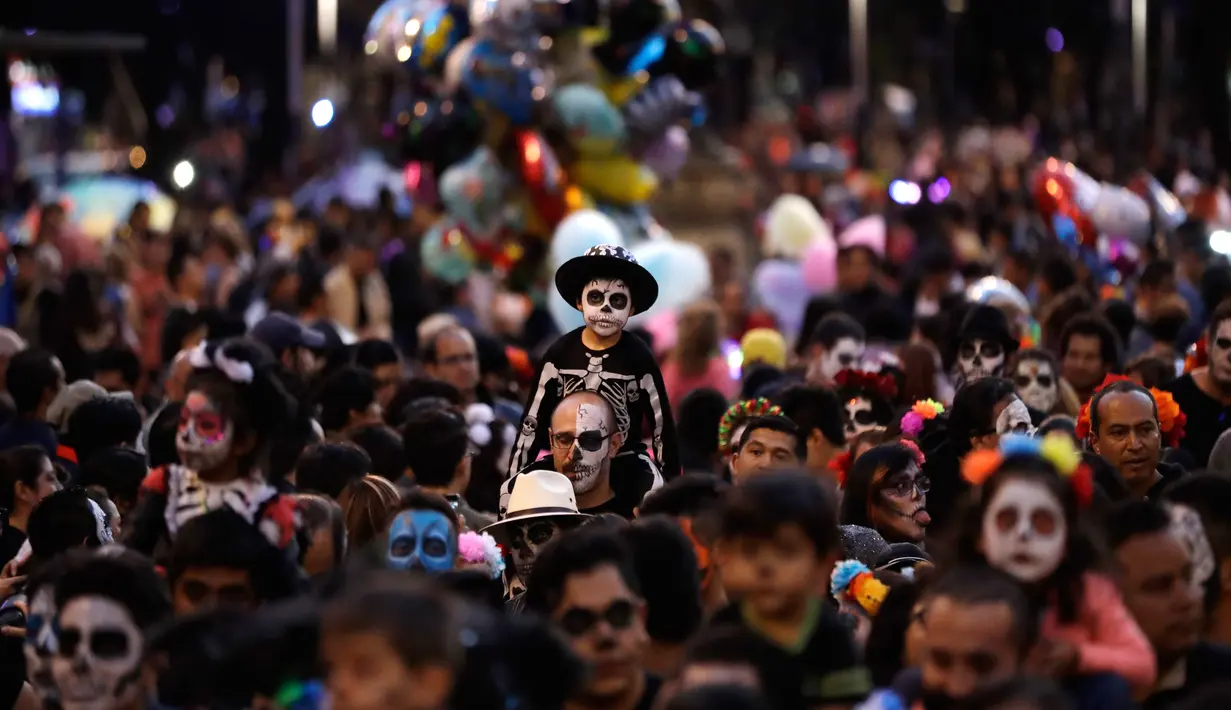 Orang-orang mengenakan kostum tengkorak berbaris mengikuti Prosesi Grand Catrinas, untuk menandai perayaan Day of The Dead, di Mexico City, Minggu (22/10). Dalam prosesi tersebut warga berdandan menyerupai kerangka. (AP/Rebecca Blackwell)