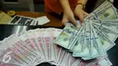 Petugas menunjukkan uang pecahan US$100 di penukaran uang, Jakarta, Rabu (12/8/2015). Reshuffle kabinet pemerintahan Jokowi-JK, nilai rupiah terahadap Dolar AS hingga siang ini menembus Rp 13.849. (Liputan6.com/Johan Tallo)