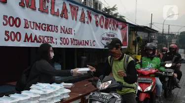 Warga menerima pembagian nasi bungkus gratis di Posko Perjuangan Rakyat (POSPERA), Jakarta, Rabu (10/3/2021). Pembagian 500 nasi bungkus beserta masker dan vitamin secara gratis setiap harinya dalam bentuk meringankan beban warga di tengah pandemi Covid-19. (merdeka.com/Imam Buhori)