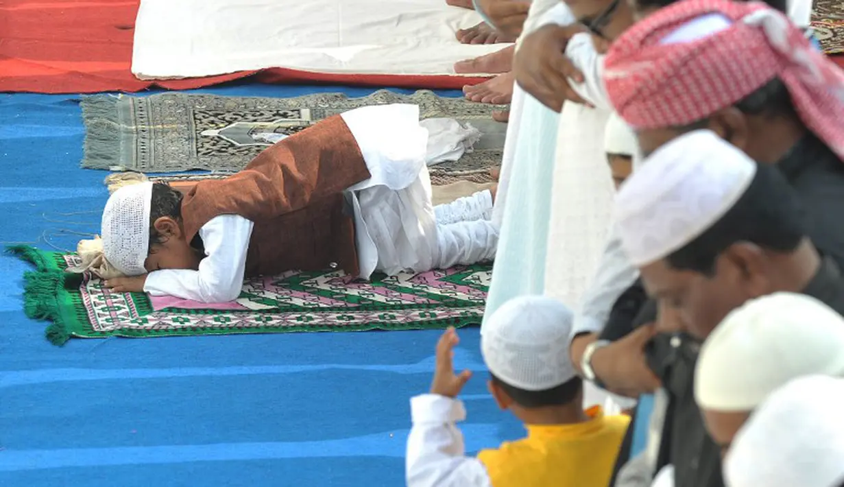 Bocah berbaju coklat ini asyik sujud sendiri ketika semua jamaah sedang berdiri. Kawannya yang berbaju kuning terlihat bingung, Hyderabad, India, Senin (6/10/2014) (AFP Photo/Noah SEELAM) 