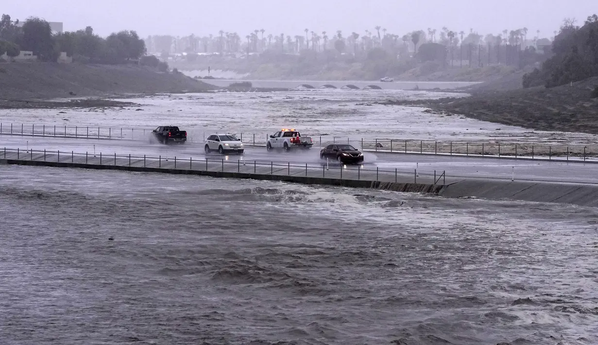 Kendaraan melintasi cekungan pengendali banjir yang hampir mencapai jalan di Palm Desert, California, Minggu, 20 Agustus 2023.(AP Photo/Mark J. Terrill)