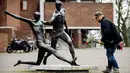 Seorang pria akan meletakan bunga di depan patung Johan Cruyff yang terdapat di sekitar Stadion Amsterdam Arena, Amsterdam, Kamis (24/3/2016). Mantan bintang timnas Belanda itu meninggal pada usia 68 tahun. (AFP/Koen Van Weel)