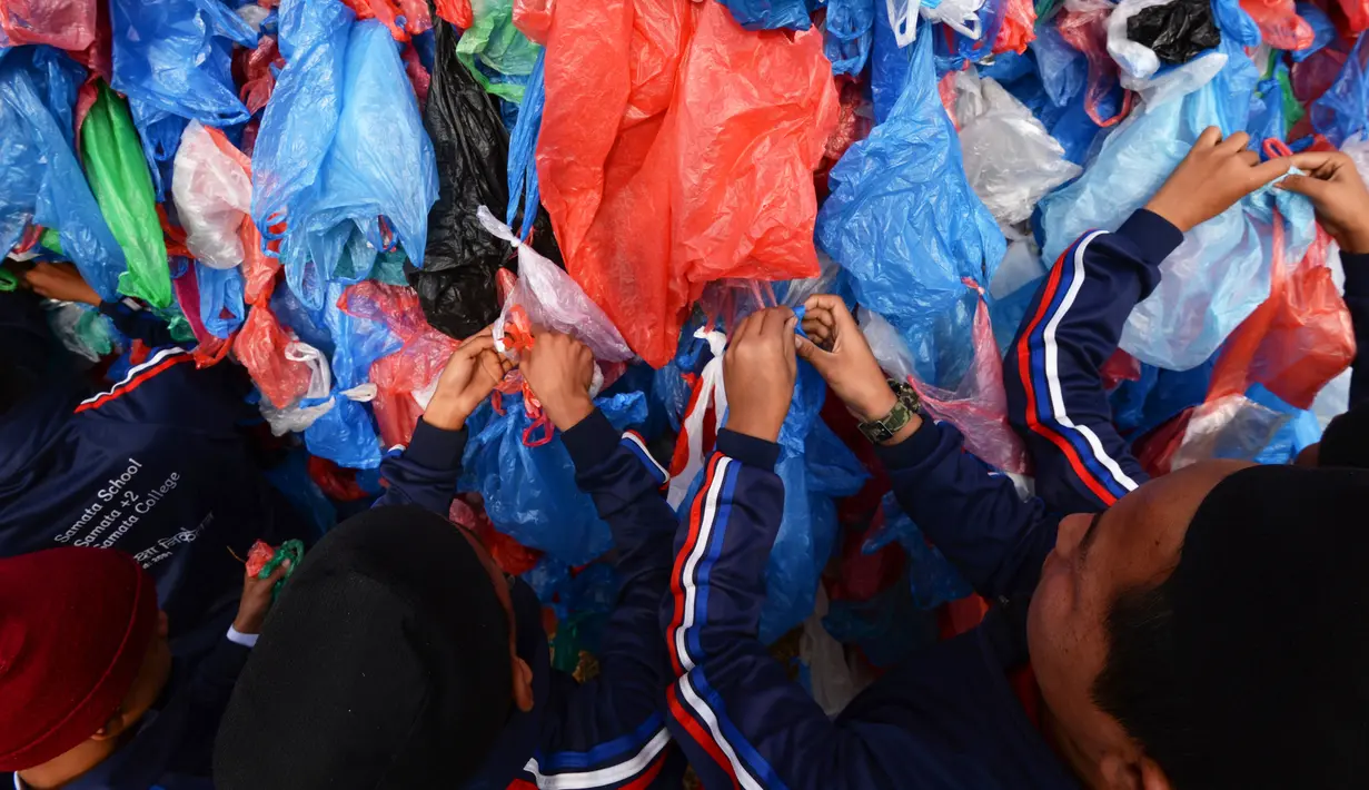 Relawan Nepal dan siswa sekolah membuat replika Laut Mati dari plastik daur ulang di Kathmandu pada 5 Desember 2018. Mereka mengikat 100.000 kantong plastik bekas berwarna-warni untuk upaya pembuatan rekor dunia baru. (PRAKASH MATHEMA / AFP)