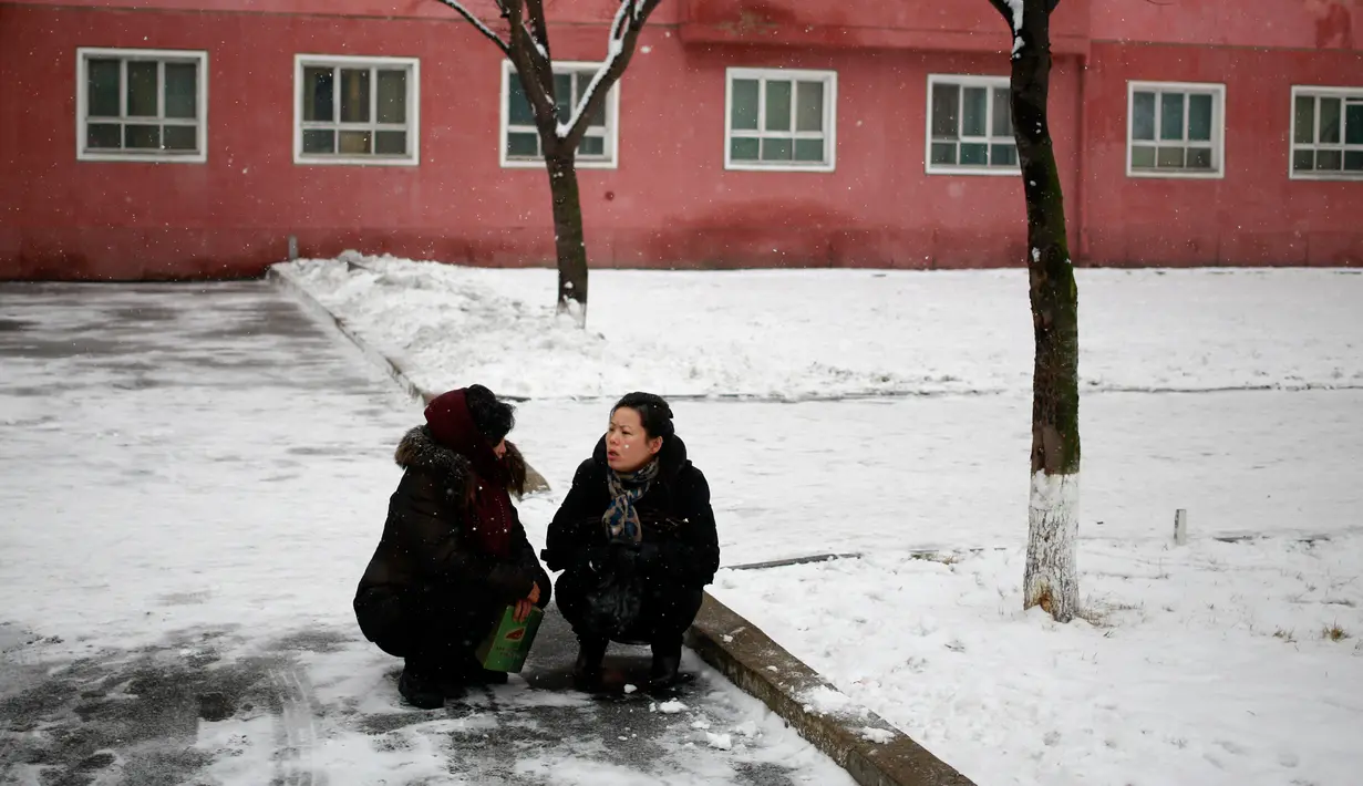 Dua orang wanita mengobrol di bawah pohon di Pyongyang, Korea Utara, Minggu (16/12). Korea Utara saat ini mulai memasuki musim dingin. (AP Photo/Dita Alangkara)
