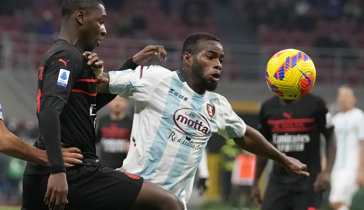 Bek AC Milan, Fode Ballo-Toure berebut bola dengan pemain Salernitana, Lassana Coulibaly pada pertandingan lanjutan Liga Serie A Italia di stadion San Siro, di Milan, Italia (4/12/2021). Hasil ini membuat AC Milan untuk sementara berada di puncak klasemen dengan 38 poin. (AP Photo/Antonio Calanni )