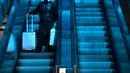 Seorang pelancong yang mengenakan masker untuk melindungi dari penyebaran virus korona menaiki eskalator di bawah jendela atap berwarna di Stasiun Kereta Api Beijing di Beijing, Kamis (28/1/2021).  Upaya untuk mencegah warga Tiongkok bepergian untuk Tahun Baru Imlek tampaknya berhasil. (AP Photo/Mar