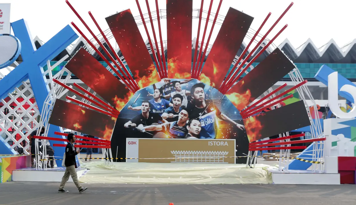 Pekerja melintas di depan ornamen pintu masuk jelang pelaksanaan turnamen Indonesia Open 2019 di Istora Senayan, Jakarta, Senin (15/7/2019). Indonesia Open 2019 akan dihelat pada 16-21 Juli 2019. (Liputan6.com/Helmi Fithriansyah)