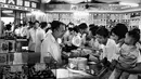 Pekerja melayani pelanggan di sebuah toko kue selama jam sibuk di Shanghai, China pada 24 September 1974. (AFP Photo)