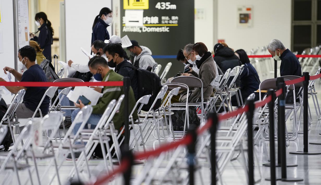 Anggota staf membantu penumpang mempersiapkan dokumen mereka selama proses karantina pencegahan virus corona mereka setelah mendarat di Bandara Internasional Narita di Narita, timur Tokyo, Jepang (2/12/2021). (AP Photo/Hiro Komae)