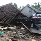 Dua unit mobil tertimbun reruntuhan rumah yang rusak setelah tsunami menerjang kawasan Anyer, Banten, Minggu (23/12). Data sementara jumlah korban dari bencana tsunami di Selat Sunda tercatat 168 orang meninggal dunia. (Liputan6.com/Angga Yuniar)