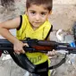 Seorang bocah Azaz bermain dengan senapan AK-47 milik ayahnya beberapa km 47 (29 mil) Utara Aleppo. (Reuters/Goran Tomasevic/wwn)